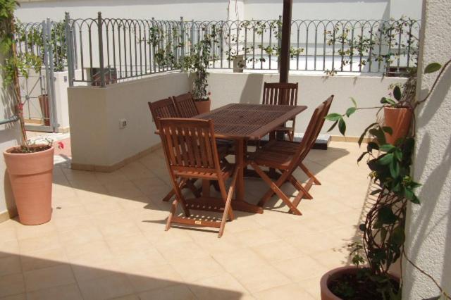 切萨雷奥港Residence La Corte的种有植物的庭院里摆放着木桌和椅子