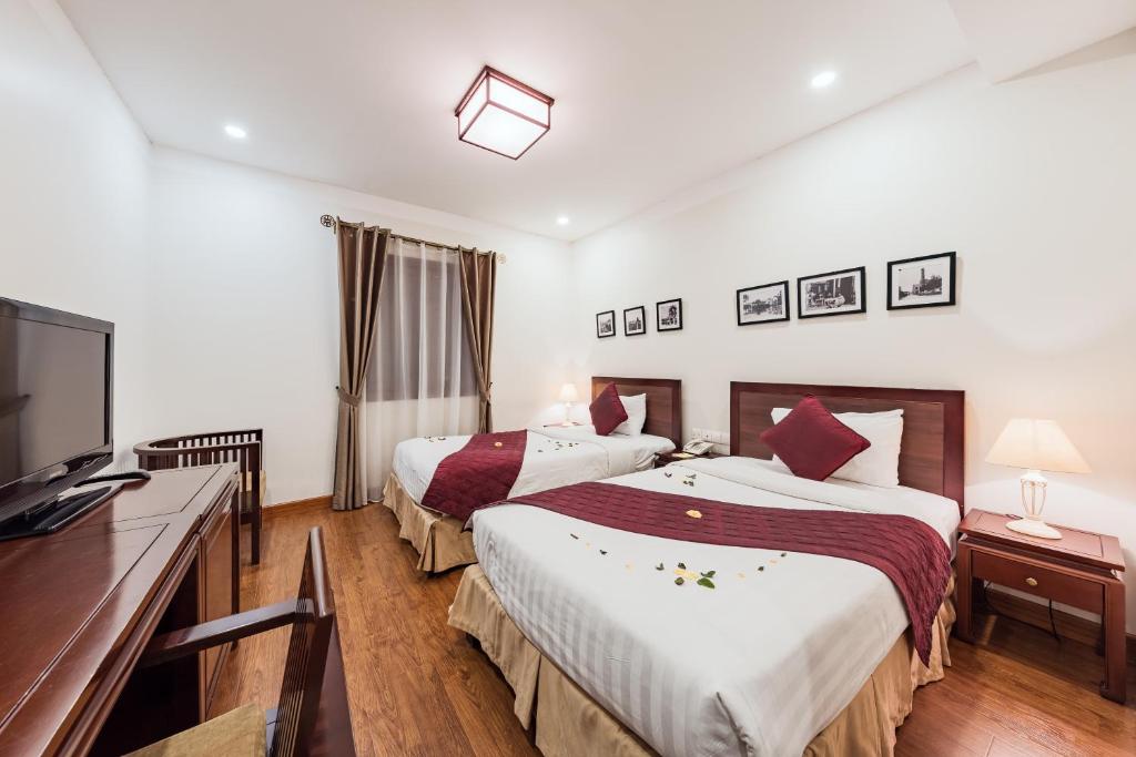 河内La Dolce Vita Hotel的酒店客房设有两张床和一台平面电视。