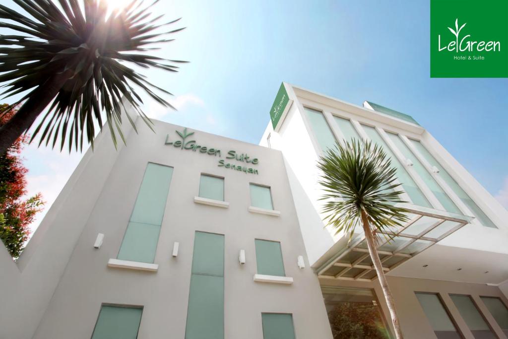 雅加达塞纳扬拉格林套房酒店的一座白色的建筑,前面有棕榈树