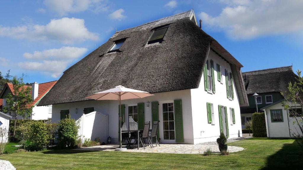 卡尔斯哈根Ahornweg 7a的白色的房子,有黑色的屋顶和雨伞