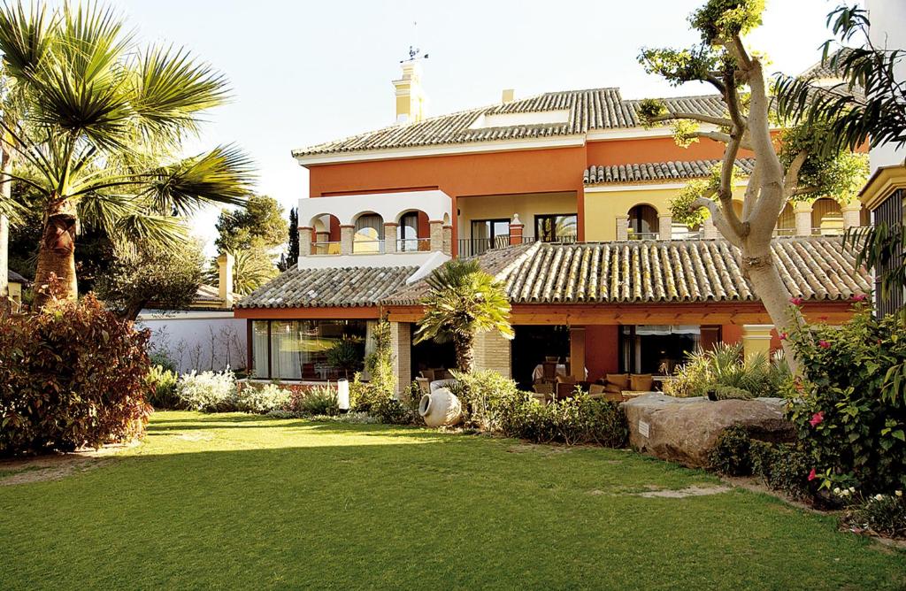 圣玛丽亚港Apartamentos Soho Boutique Vistahermosa的一座种植了棕榈树的大型橙色房子和庭院