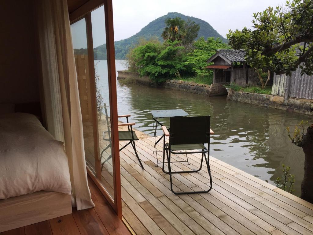 京丹后市Waterside Cottage Heron的一间设有一张床的客房,甲板上配有一张桌子和椅子