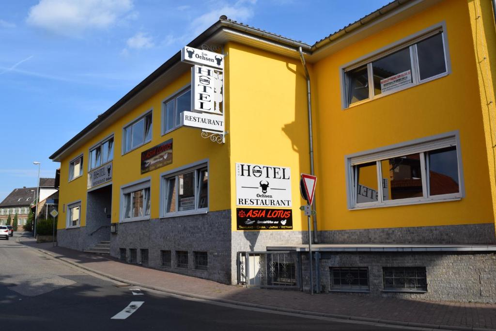 WonsheimHotel zum Ochsen的黄色的建筑,旁边标有标志