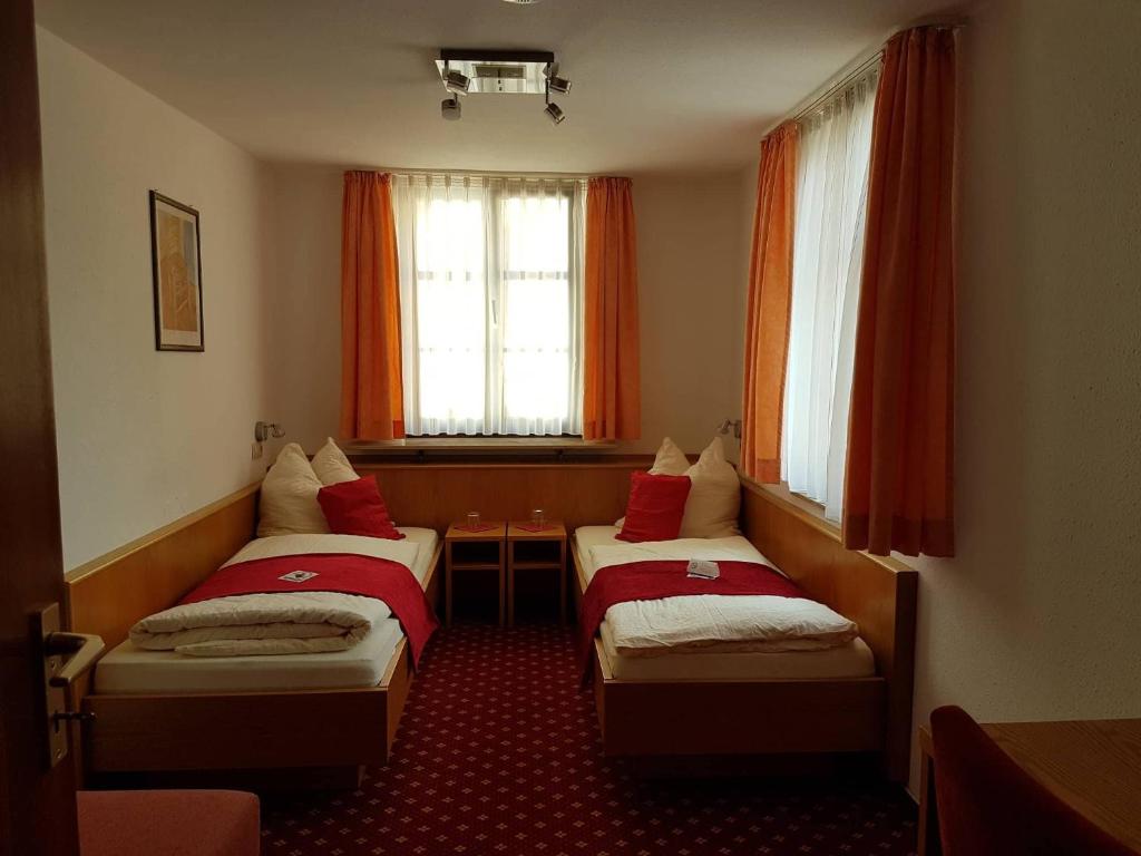 锡格马林根Hotel Traube的配有红色窗帘的酒店客房的两张床