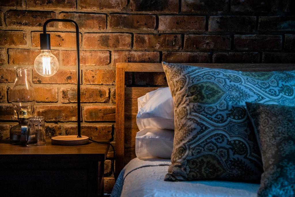 德尔斯特鲁姆Tarry-Stone Cottages的一间卧室配有一张带灯和砖墙的床