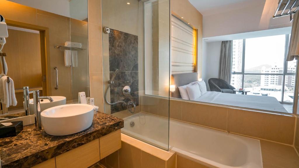 哥打京那巴鲁婆罗洲柯乐艮摄政1号酒店的一间带水槽和浴缸的浴室以及一张床