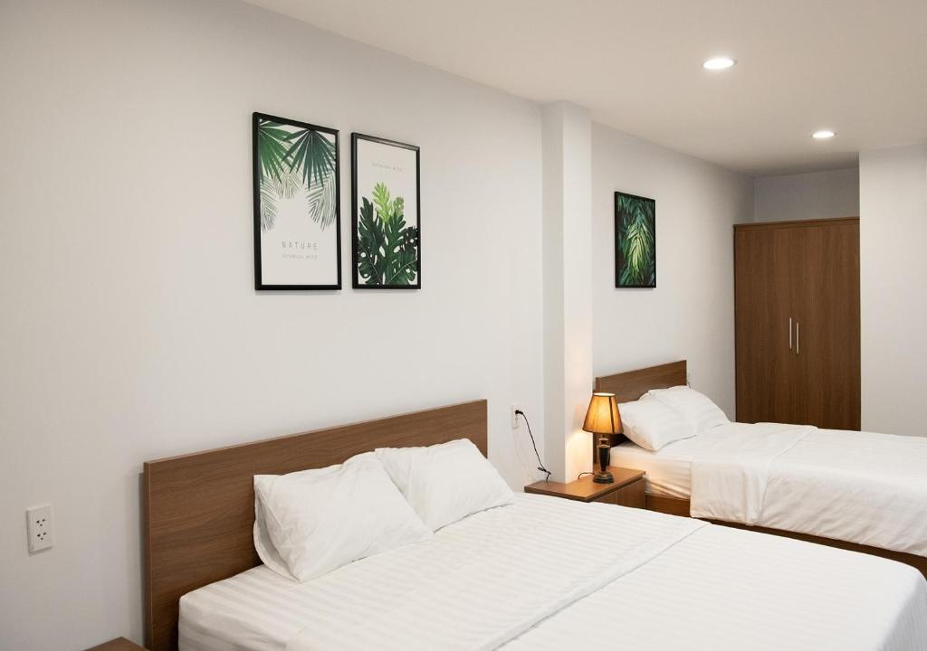 岘港Vic House Hotel的配有白色床单的酒店客房内的两张床
