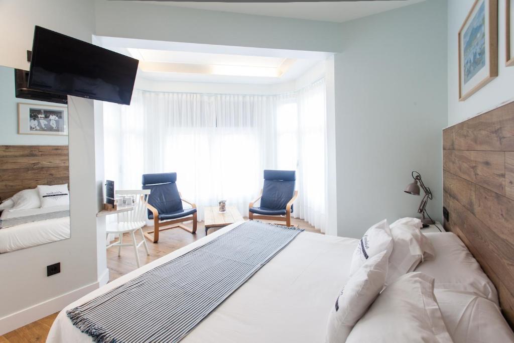 圣塞瓦斯蒂安Aldamar的白色卧室配有一张大床和两把椅子