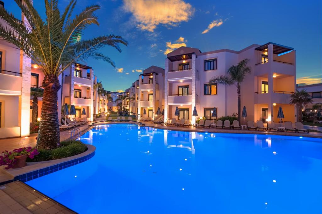 斯塔罗斯克里特棕榈度假及公寓酒店的一座棕榈树的大型游泳池位于酒店大楼前