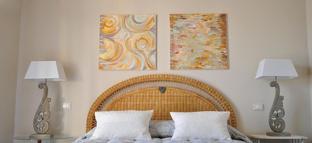 马里纳迪马萨海蓝宝石住宿加早餐旅馆的一张带两盏灯的床和墙上的两幅画