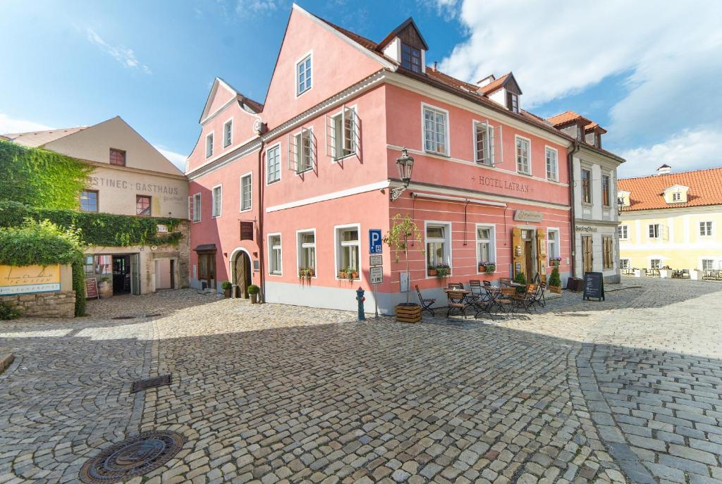 捷克克鲁姆洛夫拉特朗酒店 的鹅卵石街道上一座粉红色的大建筑