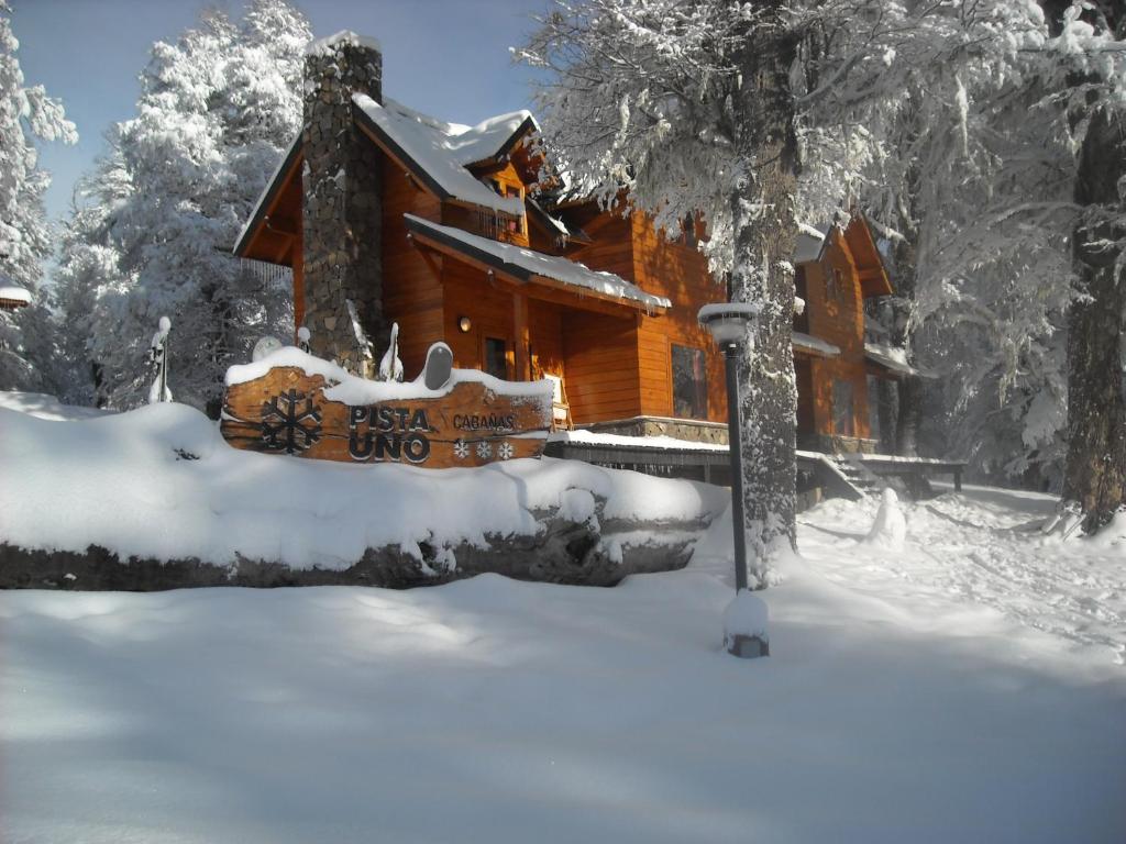 圣马丁德洛斯Cabañas Pista Uno Ski Village的雪地小木屋,前面有标志