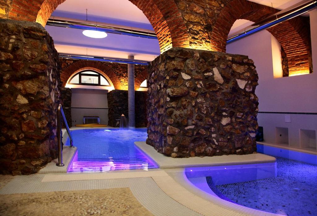 阿尔盖罗玛格丽特SPA酒店的一个带石墙和紫色灯的游泳池
