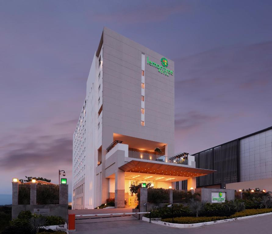 海得拉巴Lemon Tree Hotel, Gachibowli, Hyderabad的一座白色的大建筑,上面有绿色的标志