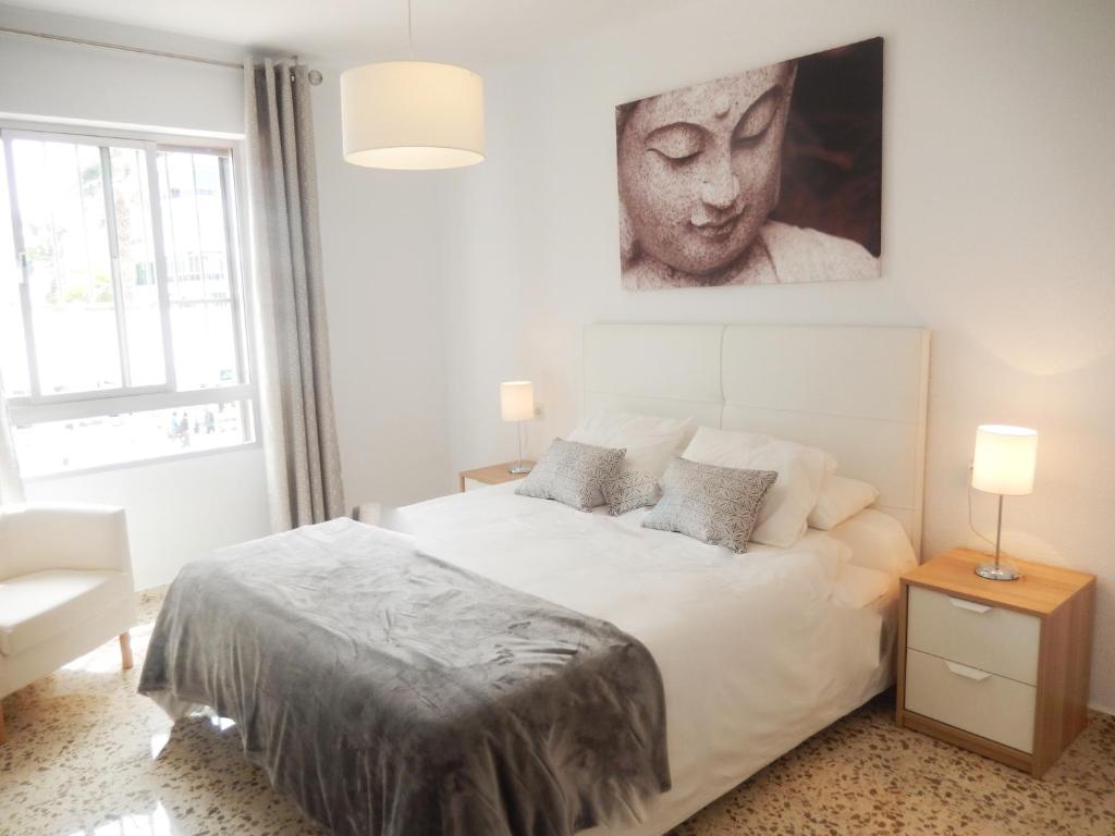 托雷德尔马尔Casa Rosa的卧室配有一张白色床,墙上挂着肖像