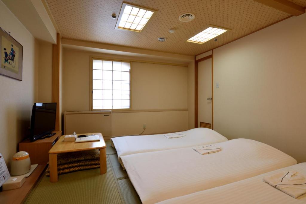 仙台Hotel Johzenji的酒店客房设有两张床和电视。