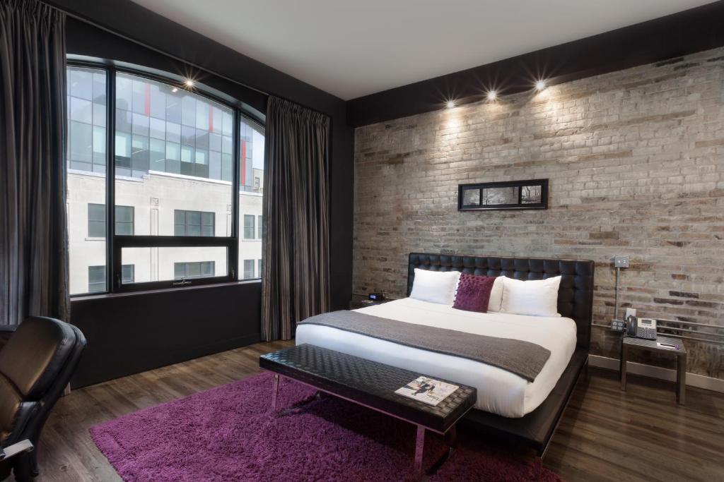 伦敦都会酒店的一间卧室设有一张大床和砖墙