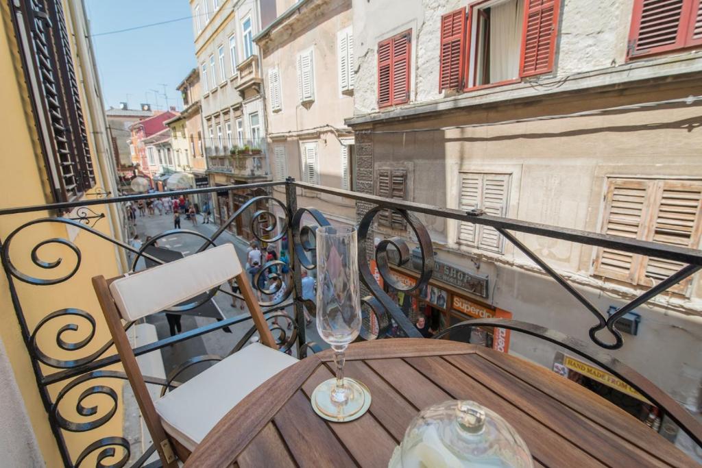 普拉Leona Deluxe Apartments的阳台上的木桌,配有葡萄酒玻璃