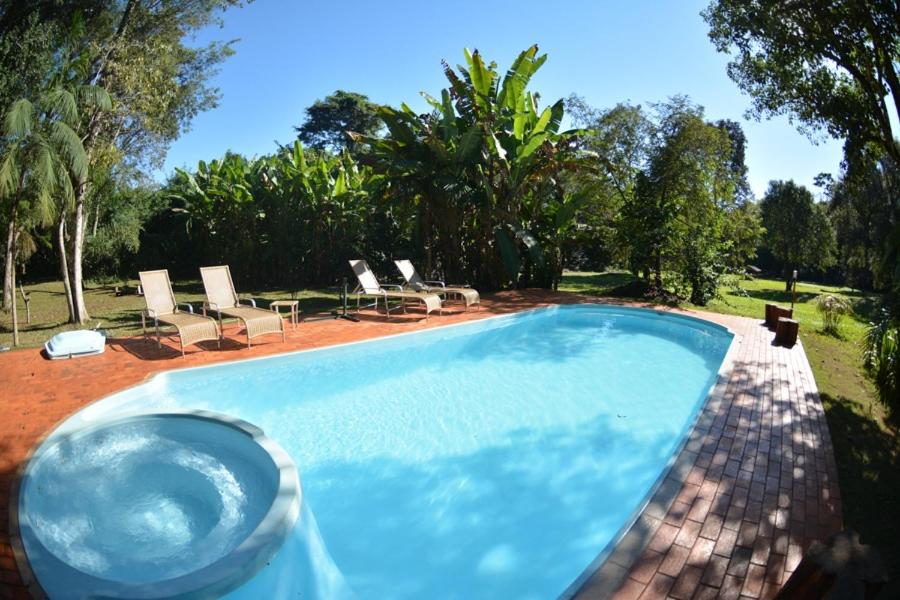伊瓜苏Iguassu Eco Hostel - IguassuEcoHostel - Eco Suítes的庭院内的游泳池,带椅子和树木
