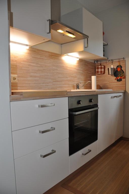 ObernhainFerienwohnung am Waldrand的厨房配有白色橱柜和黑烤箱。