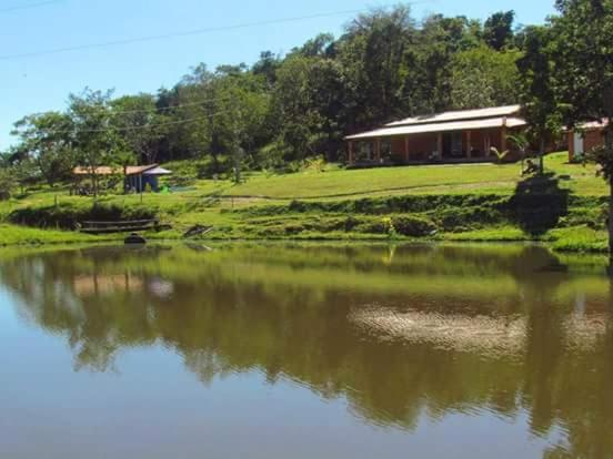 InhaúmaPousada Fazenda Bocaina的水体旁山丘上的房屋