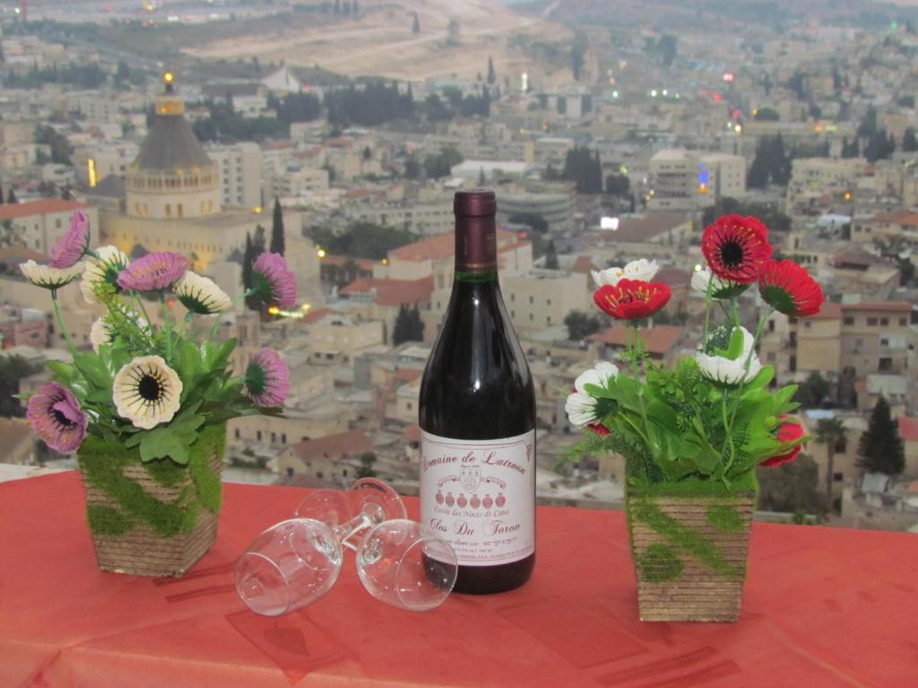 拿撒勒Royal Guest House的鲜花桌子上的一瓶葡萄酒和玻璃杯