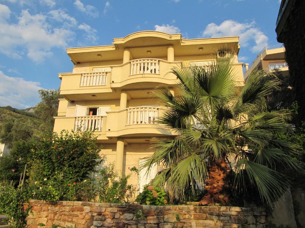 斯韦蒂·斯特凡Apartments Villa Pržno的一座黄色的建筑,前面有棕榈树