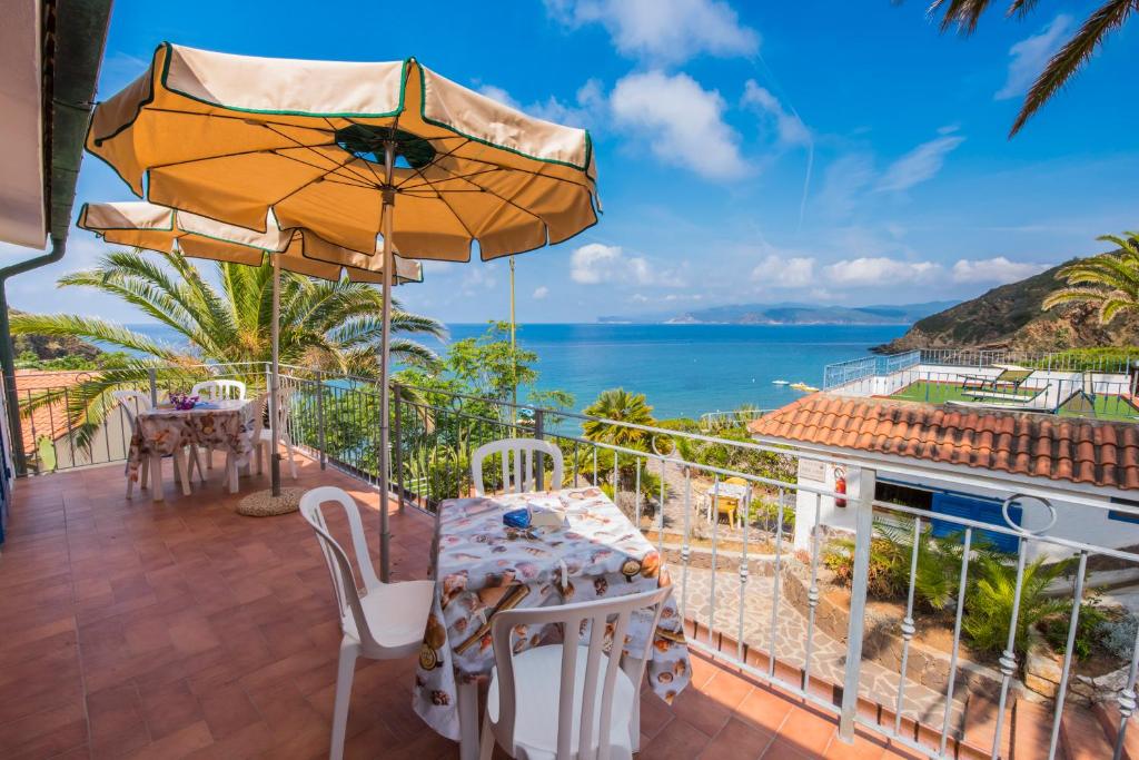 卡波利韦里Residential Hotel Villaggio Innamorata的一个带桌子和遮阳伞的庭院和大海