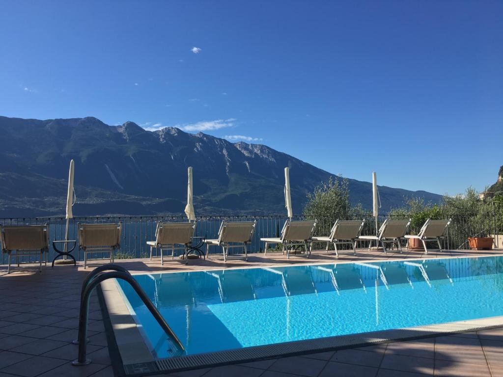 利莫内-苏尔加达Villa Belvedere Hotel的一个带椅子的游泳池,背景是山脉