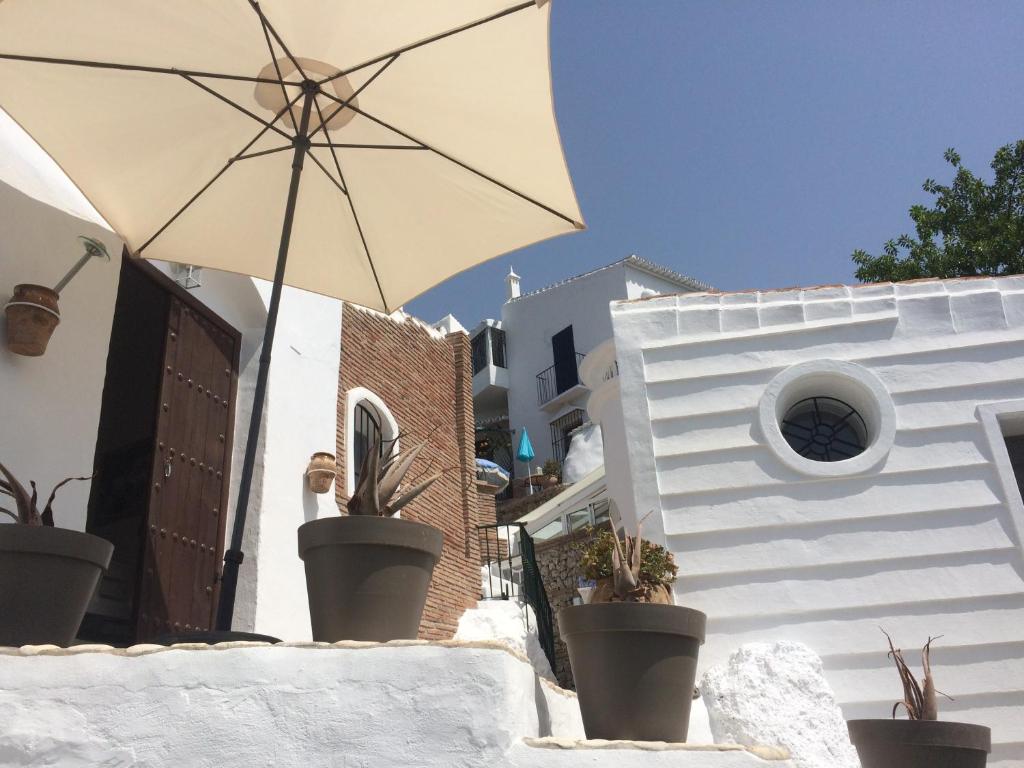弗里希利亚纳La Casa Turquesa-Original的白色的建筑,有雨伞和盆栽植物