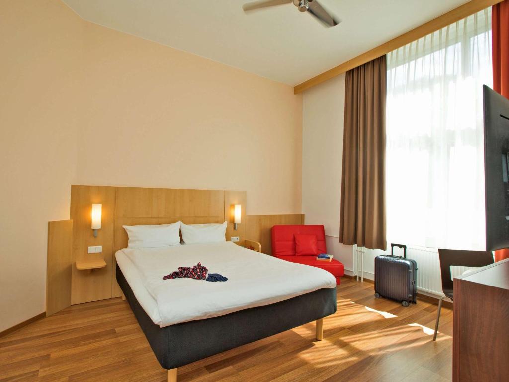 柏林ibis Berlin City Süd的酒店客房,配有一张床和一张红色椅子