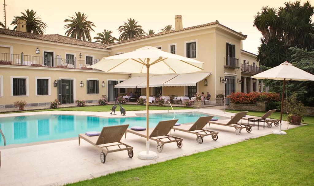 赫雷斯-德拉弗龙特拉赫雷斯别墅酒店的一座房子,设有一座带椅子和遮阳伞的游泳池