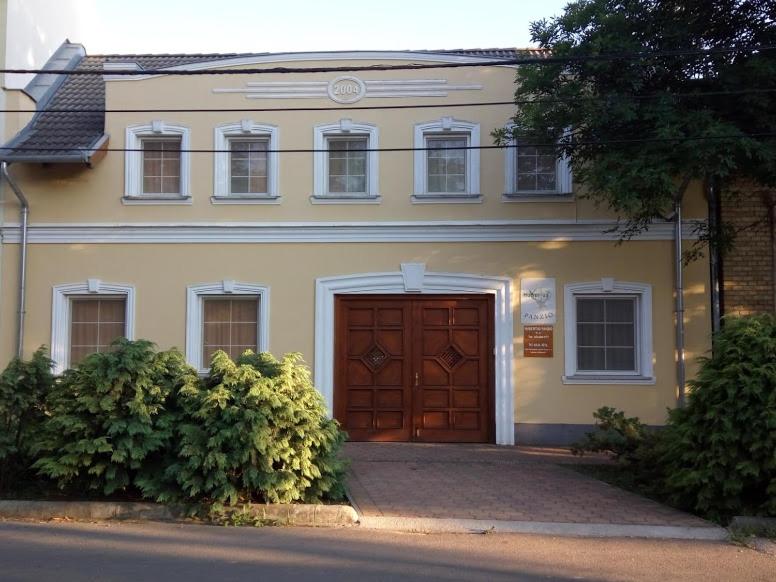 琼格拉德Hubertus Panzió的一间大房子,有一扇棕色的门和一些灌木丛