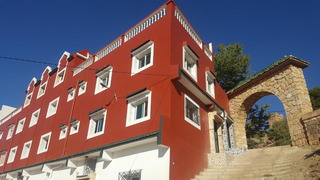 Aïn LeuhHotel Ain Leuh的一座红色和白色的建筑,有拱门