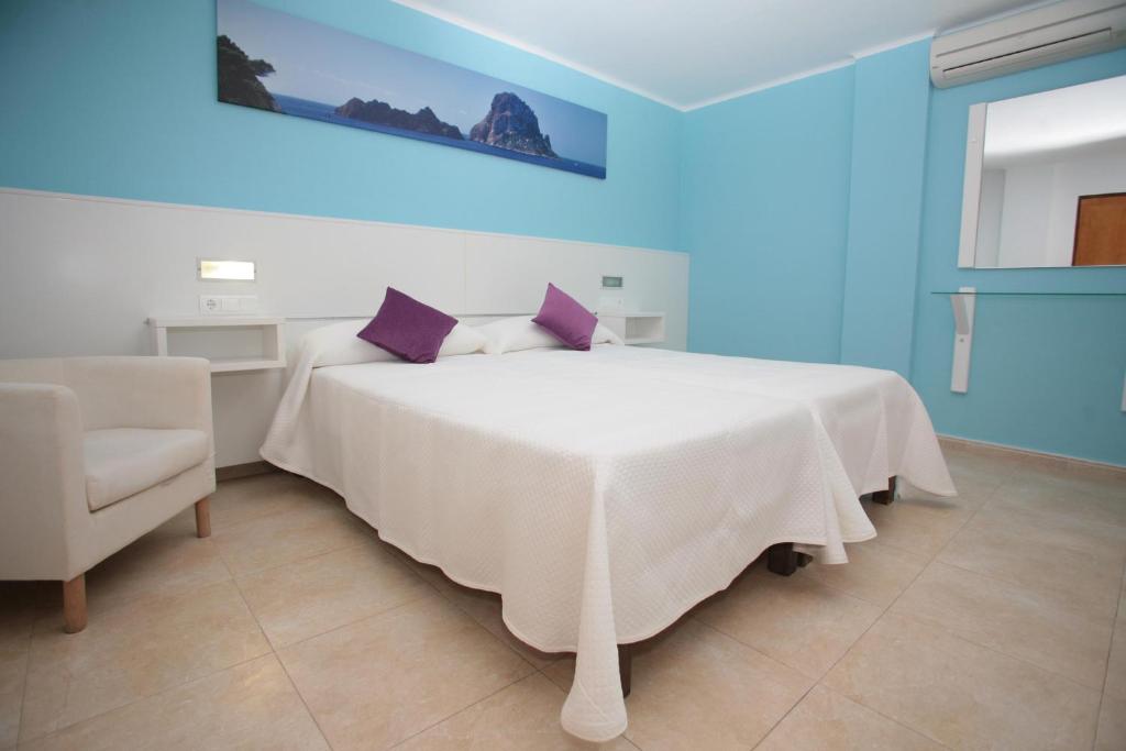 伊维萨镇白色海岸旅馆的卧室配有白色床、紫色枕头和椅子