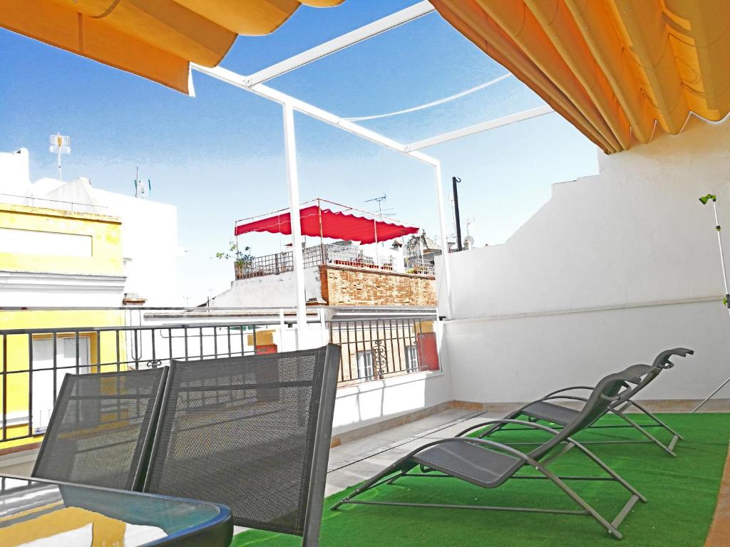 塞维利亚A2C旅舍的阳台配有椅子和红色遮阳伞