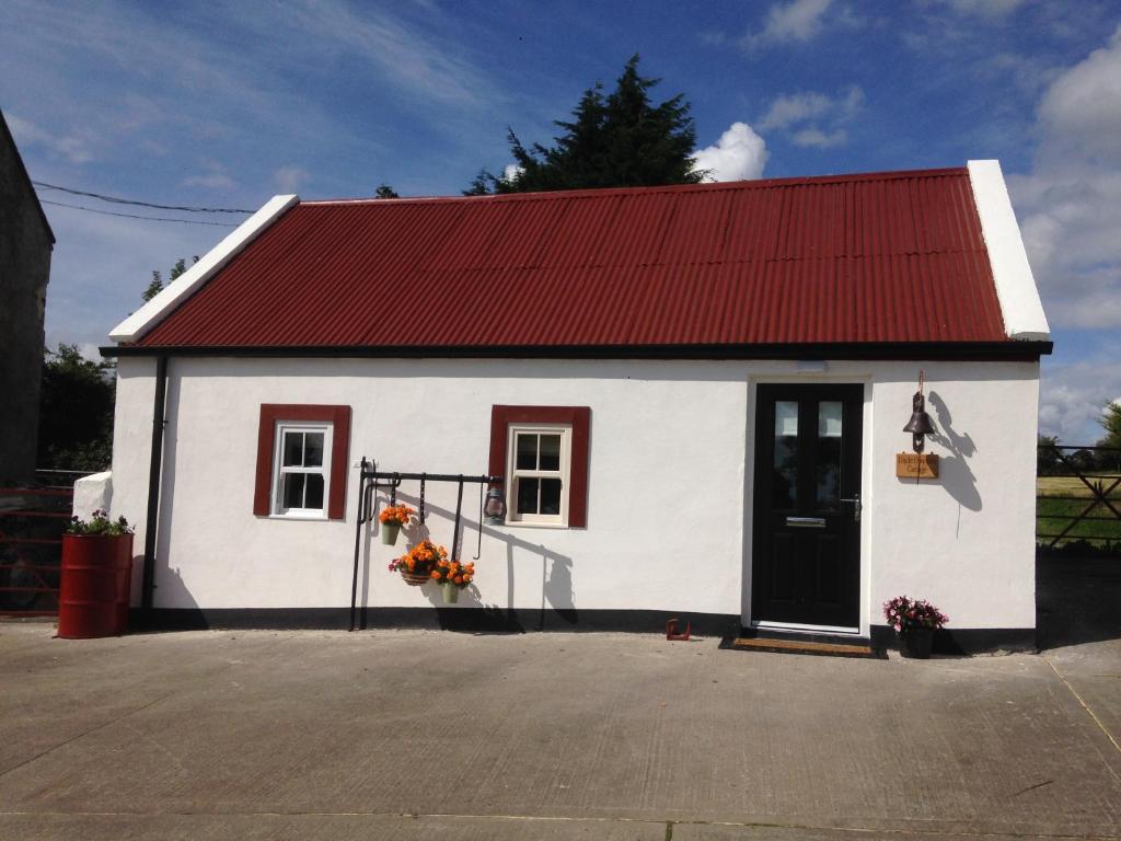 Crossmaglen'Uncle Owenie's Cottage'的一座白色的小建筑,有红色的屋顶