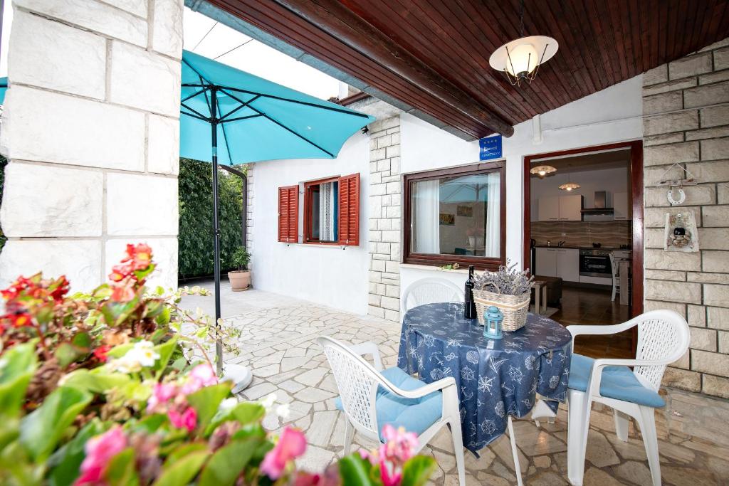 奥帕提亚Apartment Mediteraneo的庭院配有桌椅和遮阳伞。