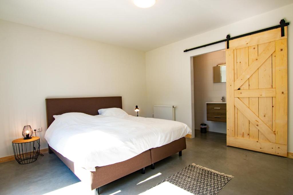 NuthBrasserie/B&B De Pletsmolen的一间卧室设有一张大床和一个滑动谷仓门