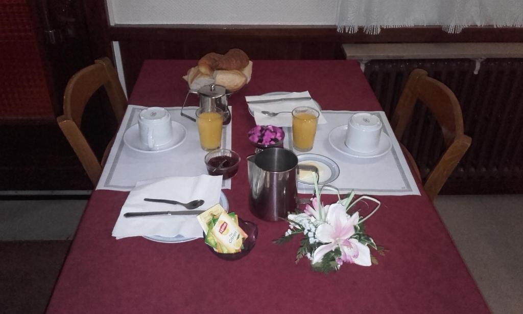 绍维尼Logis Hôtel Beauséjour的一张桌子,上面有紫色的桌布,上面有两盘盘和橙汁