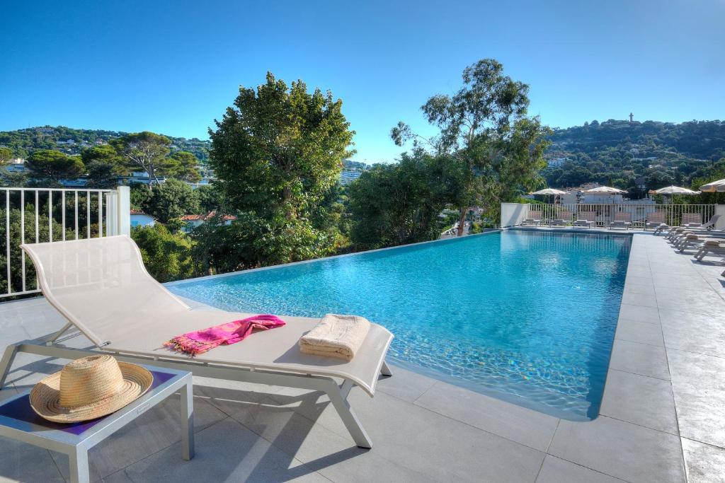 戛纳巴斯蒂奥利佛莱酒店的一个带白色椅子和桌子的游泳池