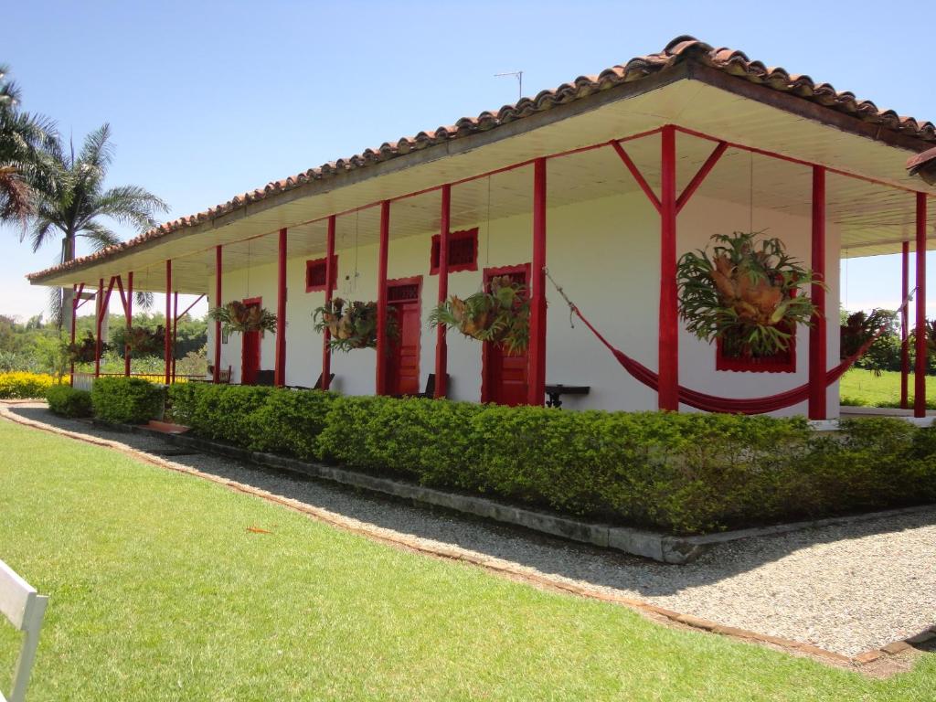 金巴亚Finca Hotel Santana Campestre的一座白色的建筑,在院子里有红色的修饰