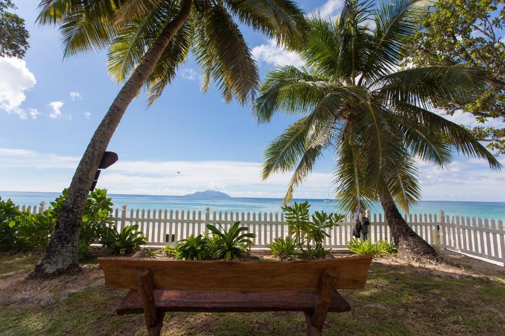 博瓦隆萨布尔斯德奥奢华公寓的木凳,坐在两棵棕榈树下,靠近大海