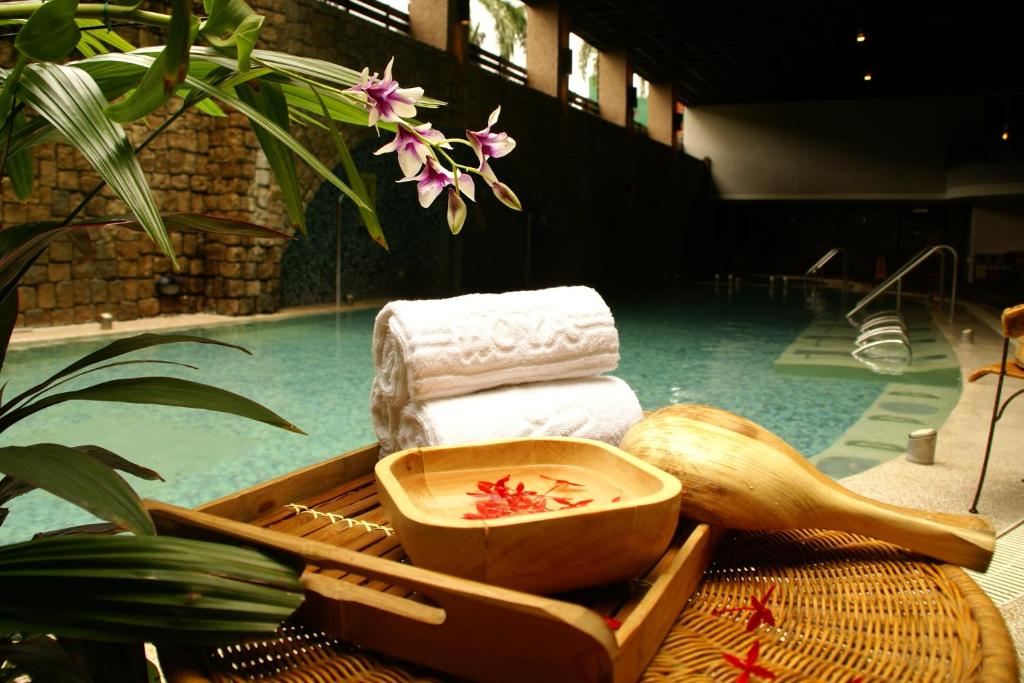 Wenquan富野温泉休闲会馆的游泳池旁的毛巾托盘和一碗水