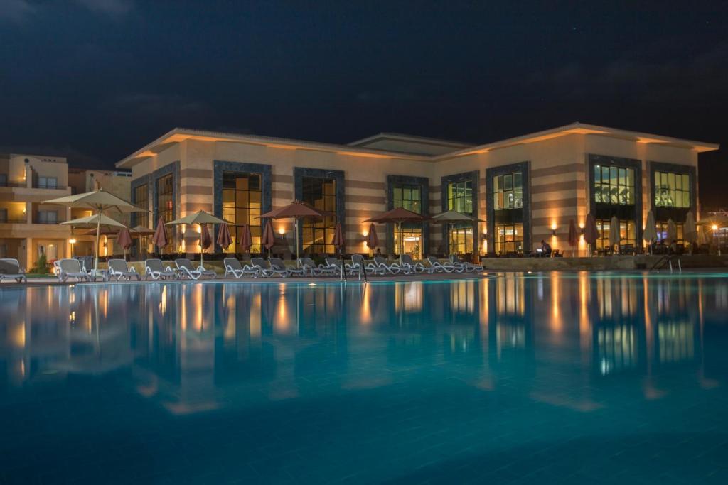 Sīdī ‘Abd ar RaḩmānAura Resort Sidi Abd El Rahman El Alamein的一座大型建筑,晚上设有游泳池