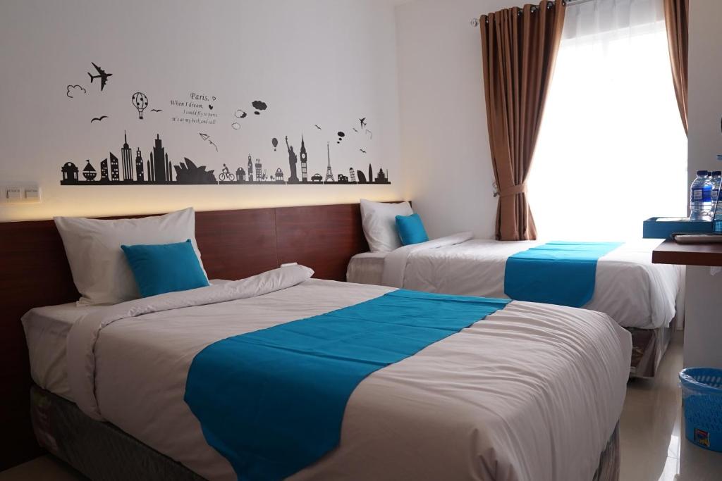 巨港Cemerlang Inn的酒店客房,配有两张蓝色和白色的床