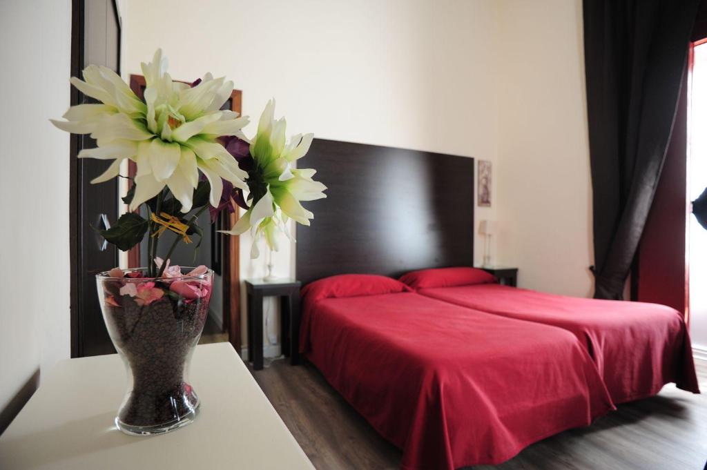 加的斯霍斯佩德利亚马尔克斯酒店的一间卧室配有红色的床和花瓶