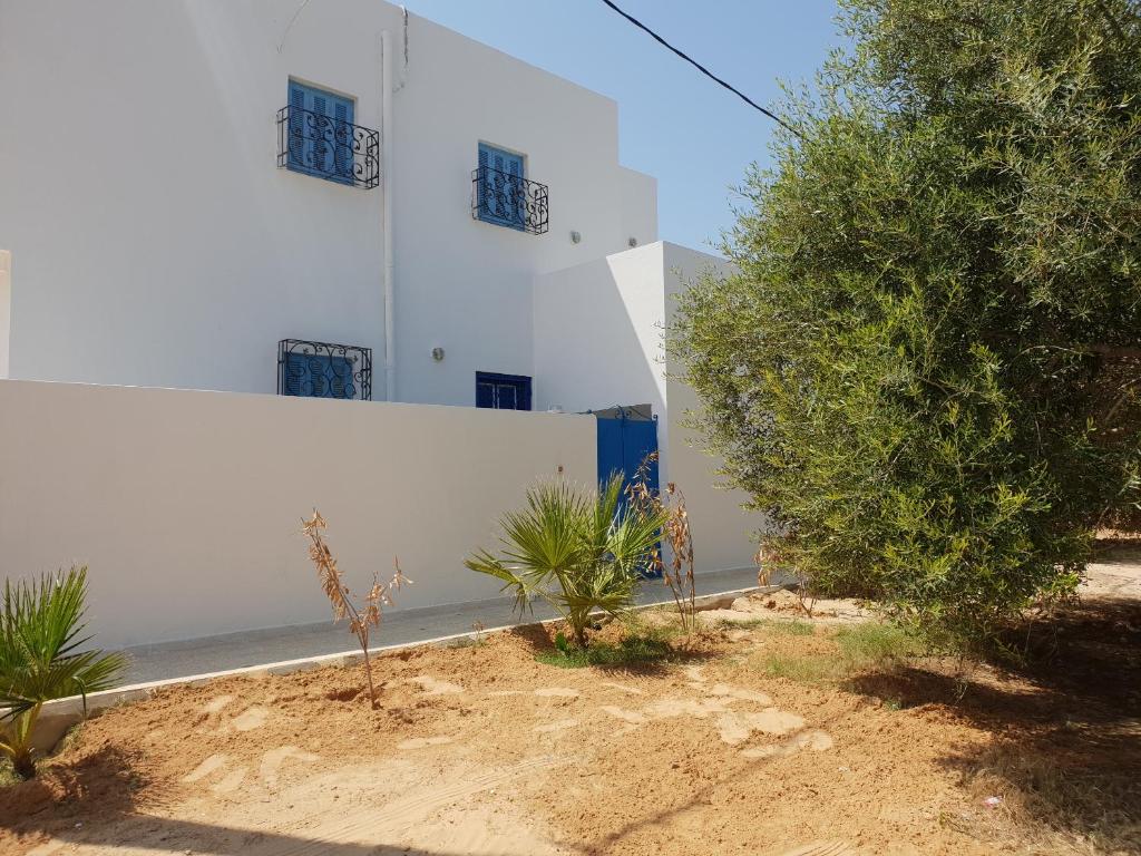 米多恩Menzel Rayan的白色的建筑,有蓝色的窗户和树