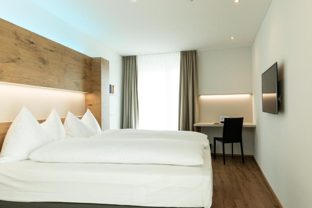 吕姆朗Jet Hotel Zurich Airport的一间酒店客房,配有一张白色的床和一张书桌