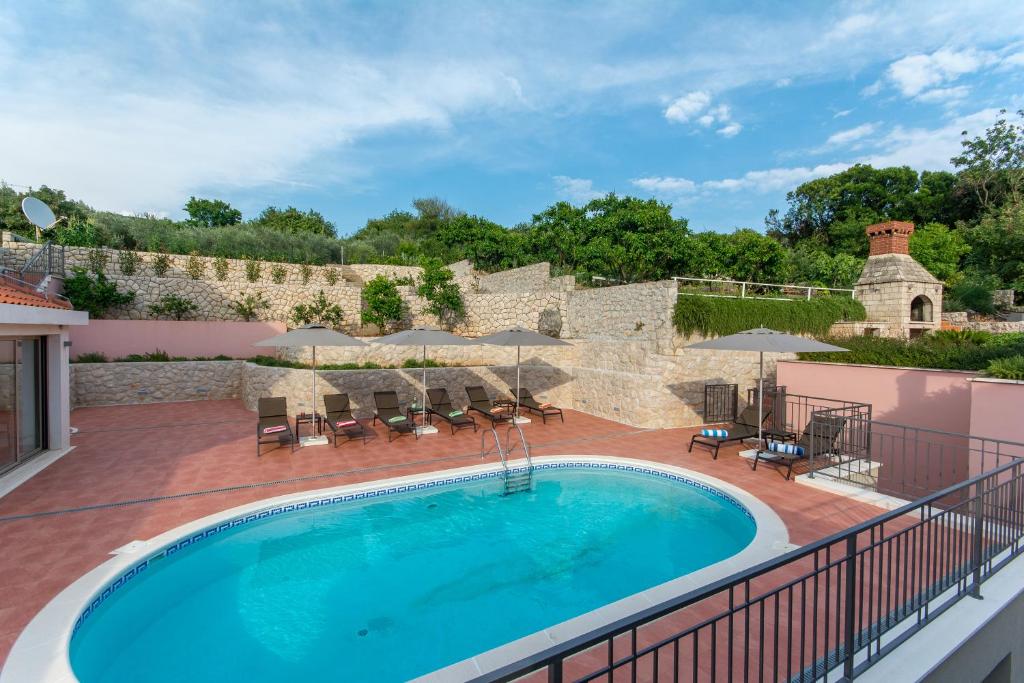 莫鲁纳特Villa Molunat的甲板上的游泳池,带遮阳伞的庭院